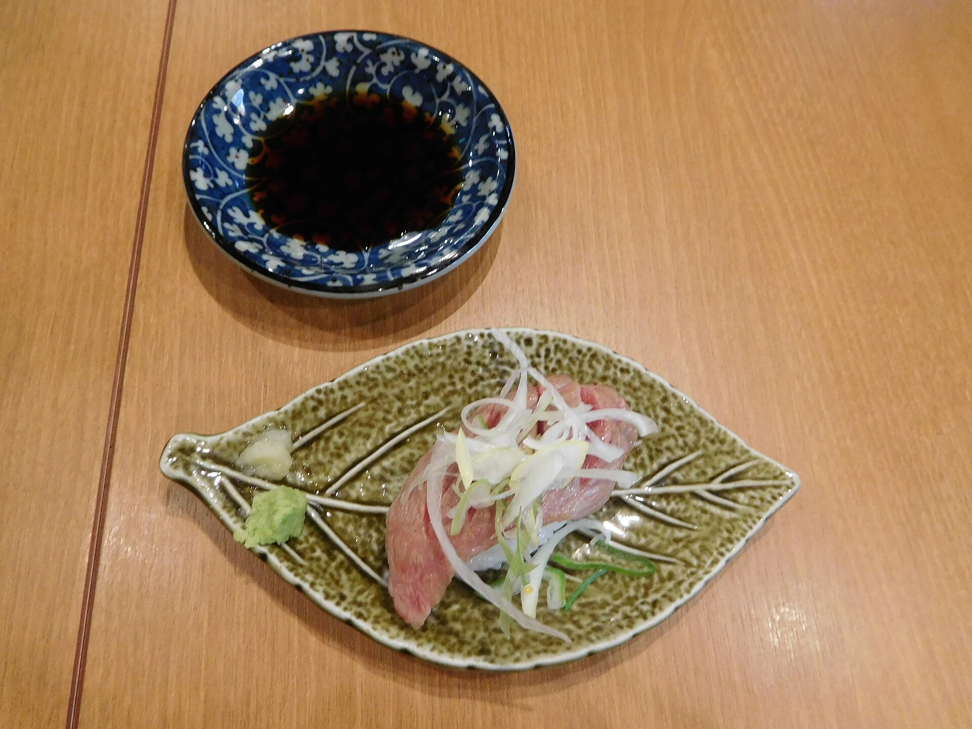 Lightly blowtorched Hida beef nigiri sushi on rice cracker