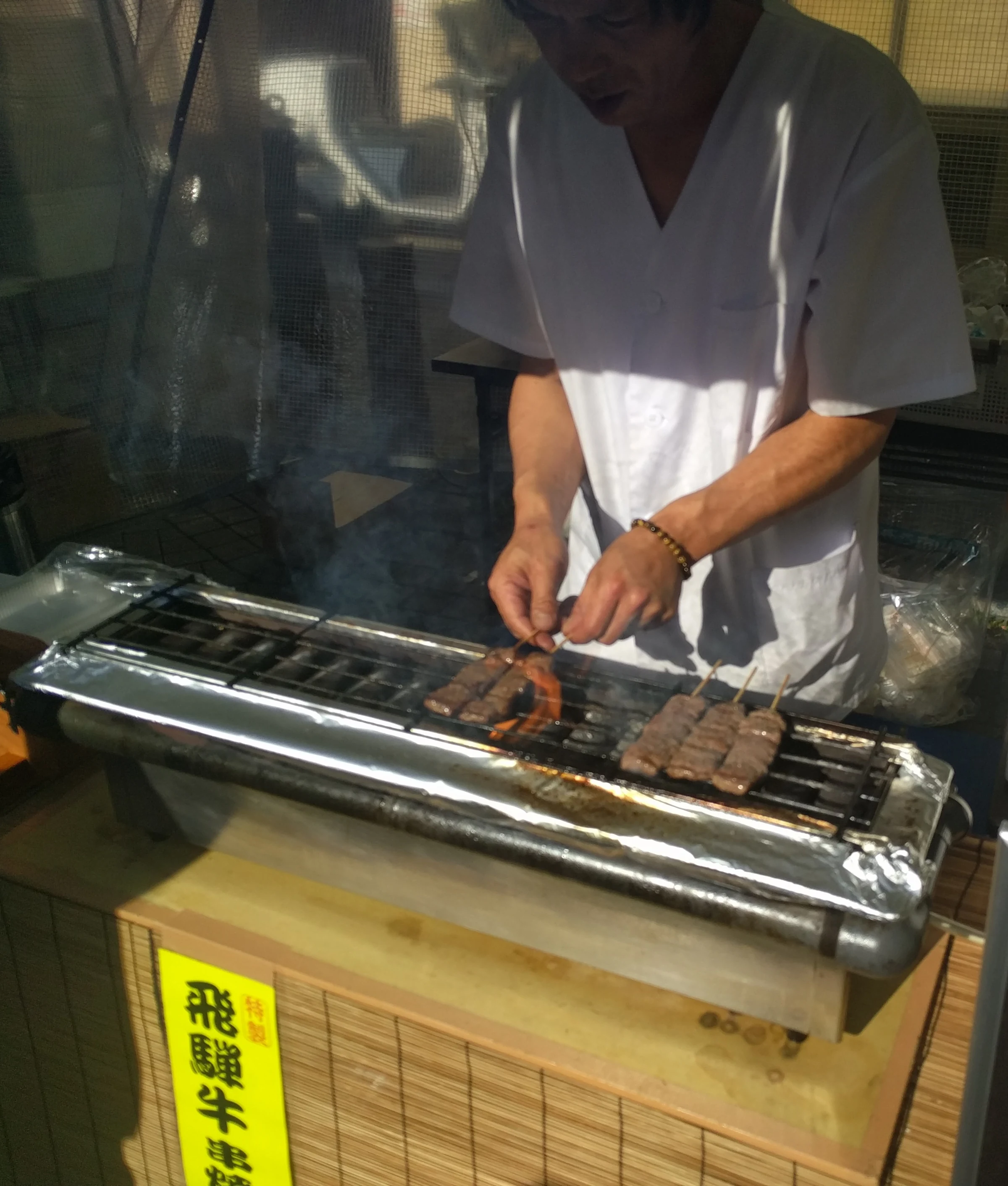 Hida beef skewers grilling at a street-food stall